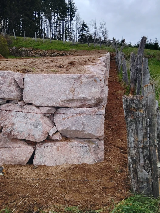 Mur de soutènement en pierres calcaires roses taillées, disposées en assises horizontales régulières