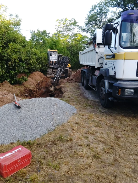 Tranchée extérieure en terre sèche révélant des infrastructures souterraines