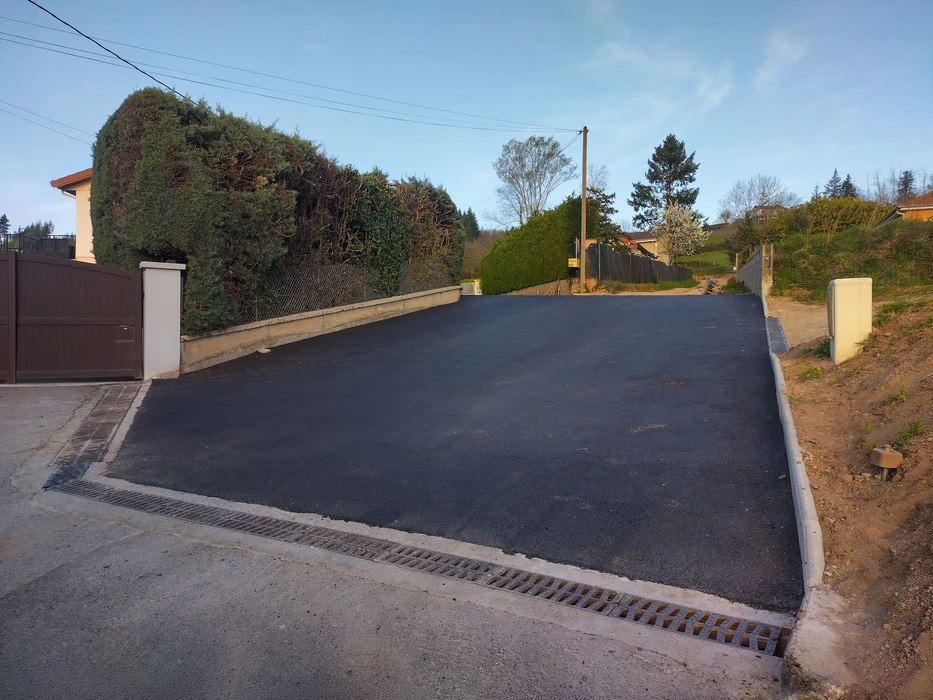 Extérieur, chaussée routière goudronnée avec marquage au sol blanc, bordée d'un mur de soutènement en béton surmonté d'une barrière métallique